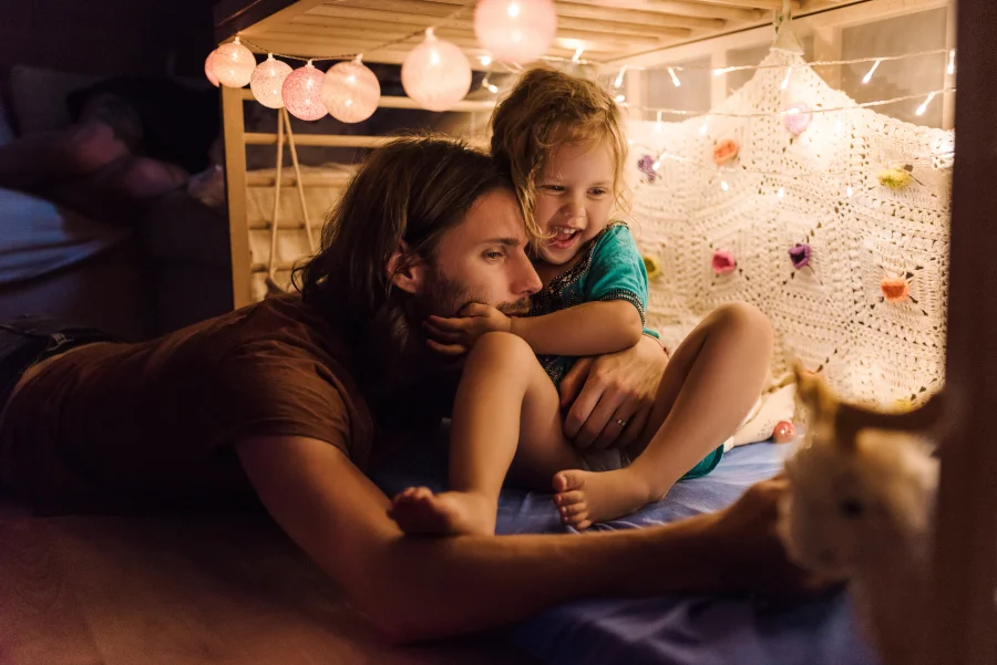 A parent and child embracing beneath string lights